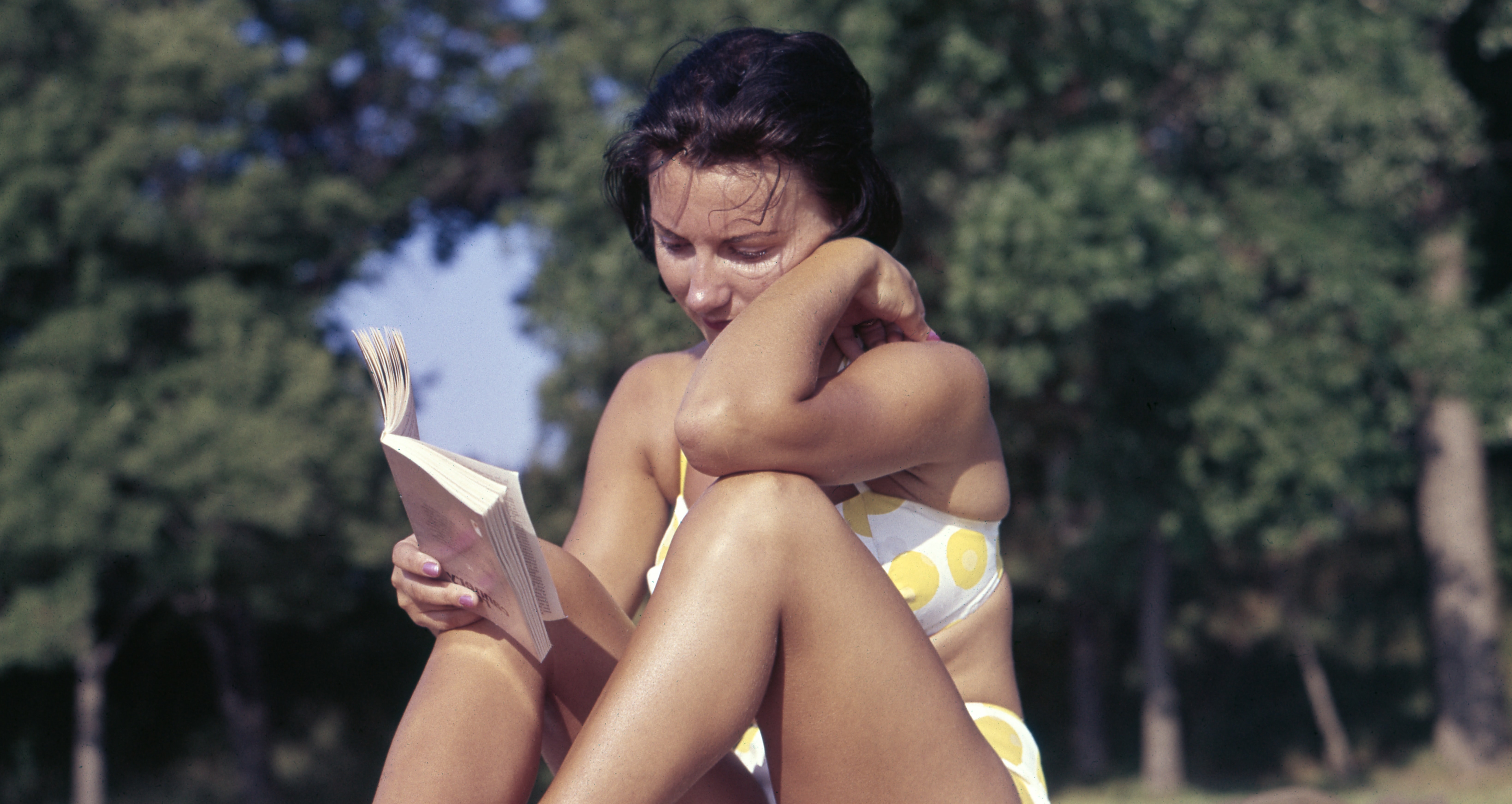 Shot of woman reading on the beach.